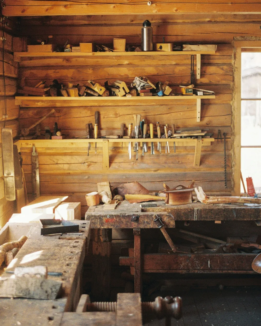 Banco de carpintero con herramientas de mano ordenadas sobre la pared de madera del taller